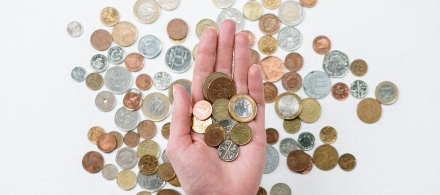 Open hand holding coins above a selection of coins