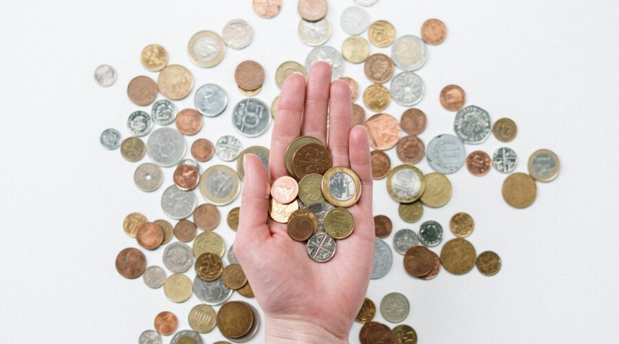 Open hand holding coins above a selection of coins